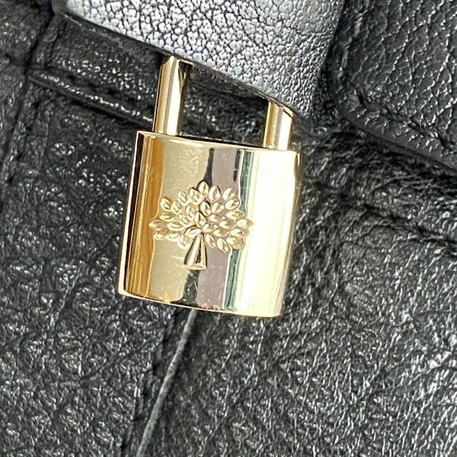 Authentic Mulberry padlock and leather tab — polished brass, a finely detailed die-struck tree with individually defined leaves, tight even stitching on the tab