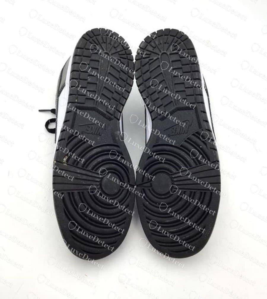 Nike Dunk Low Panda falso, vista da sola: a sola externa de borracha preta com o padrão circular de pivô, os blocos de relevo em chevron e "NIKE" em baixo-relevo no arco