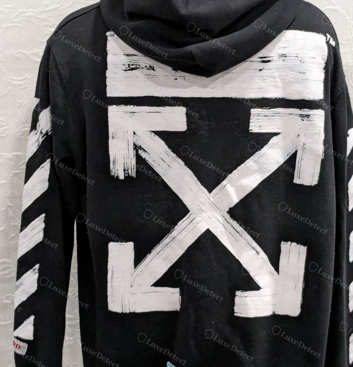 Counterfeit arrow stripe: visibly hand-brushed, uneven edges and thick-to-thin variation rather than a clean geometric line
