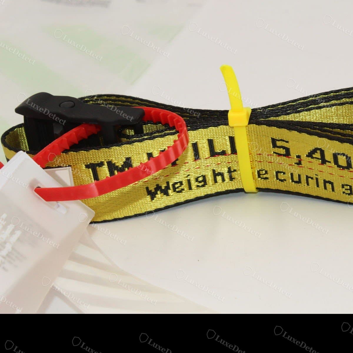 Authentic zip tie: rigid red tag printed "2013© "ZIP TIE" OFF-WHITE™" in the house typeface, attached to a matching red locking cable tie