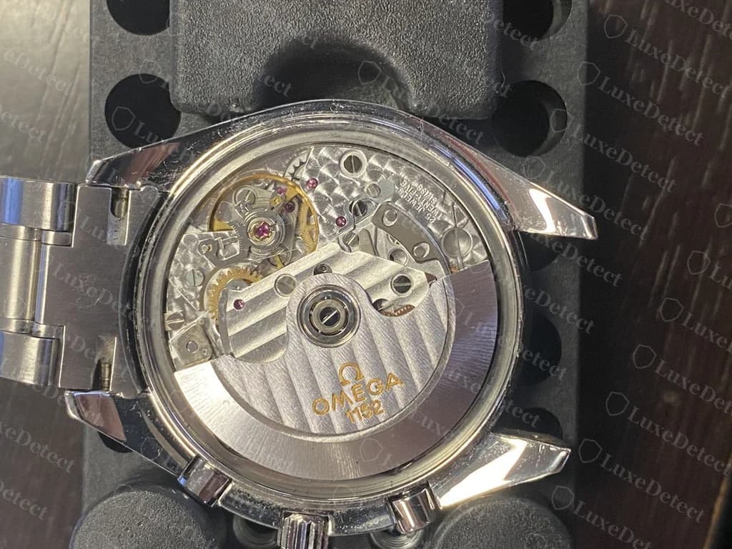 Fondo de caja abierto de un Speedmaster Date que nuestros autenticadores declararon falsificación: el rotor lleva un logo Omega y un número de calibre y los puentes parecen decorados, un recordatorio de que un movimiento de buen aspecto no prueba nada por sí solo