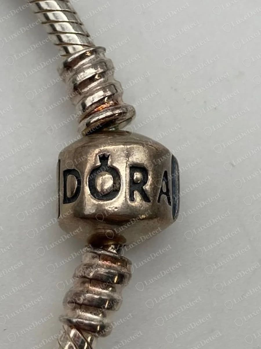 Echter Pandora Tonnenverschluss mit DORA und einer kleinen Krone über dem O, zwischen zwei Stoppern mit Gewinde an einer Schlangenkette