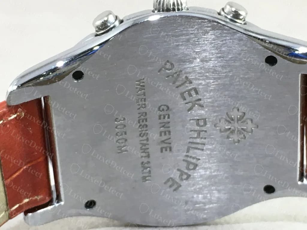 Counterfeit Patek Philippe caseback — a flat steel back with "PATEK PHILIPPE GENEVE WATER RESISTANT 3ATM" and a cross logo engraved across it and four small screws; the same watch holds a quartz movement with a coin battery