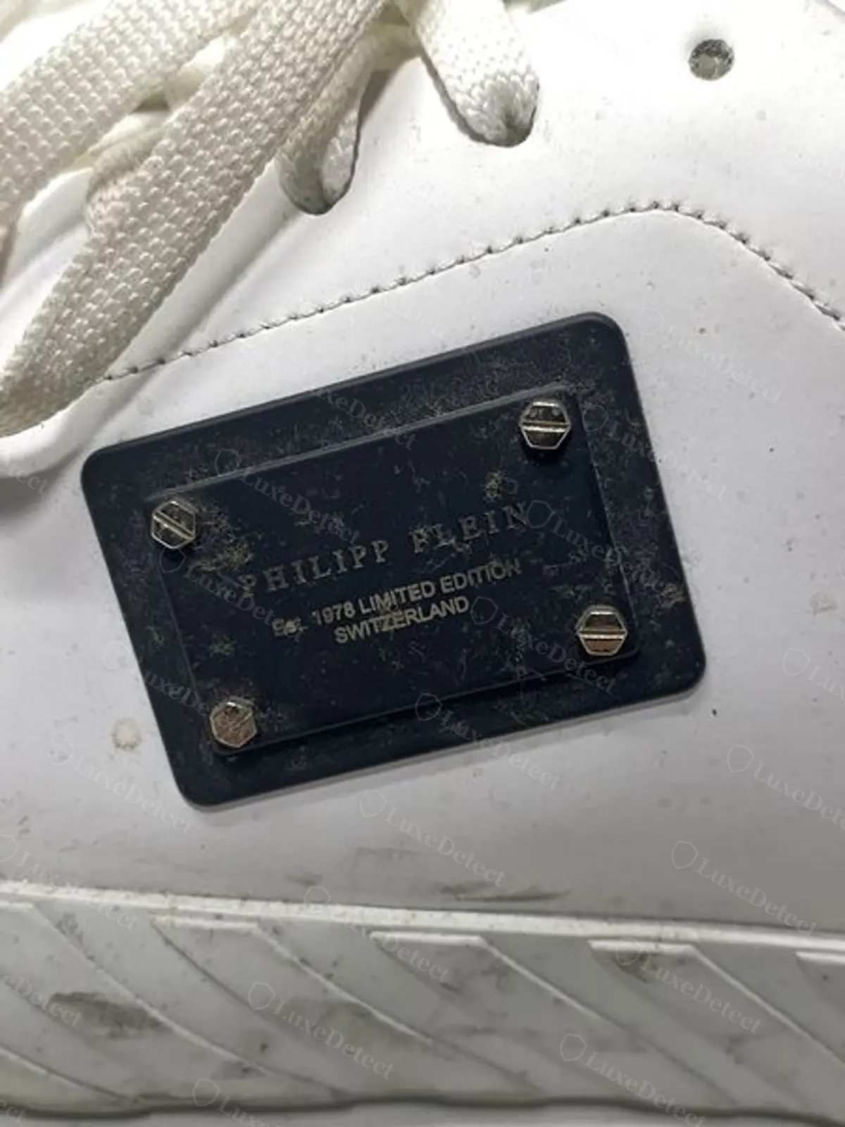 Close-up of a counterfeit plaque reading "Philipp Plein Est. 1978 Limited Edition Switzerland," a founding date and story the brand does not have