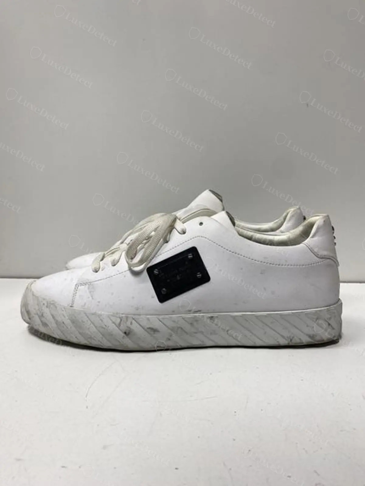 Counterfeit Philipp Plein sneaker, flat rectangular plaque riveted on with visible hex-head screws in place of an embossed hexagonal panel