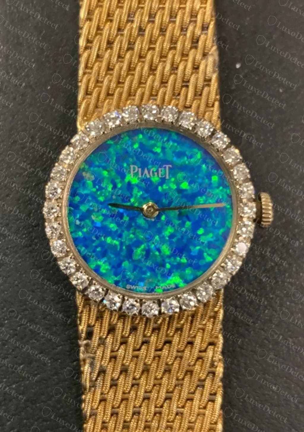 A genuine Piaget ladies' dress watch: an opal dial signed "PIAGET" with "SWISS MADE" at the bottom, a diamond-set bezel and a woven gold bracelet.