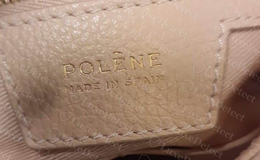 Etiqueta interior en relieve de un bolso autenticado: "POLÈNE / MADE IN SPAIN", las dos líneas en mayúsculas del mismo grosor, con una lámina de foil bien espaciada