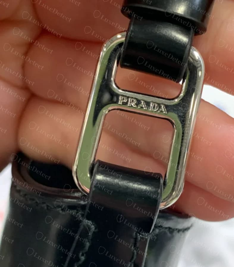 Authentic Cleo strap-loop hardware, engraved PRADA, connecting the curved top strap to the body