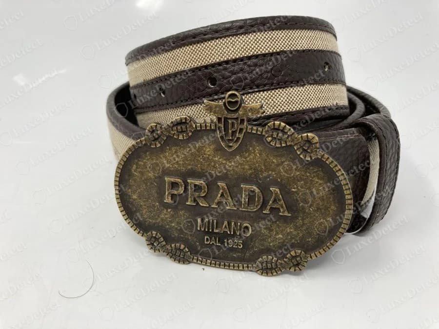 Cinturón Prada falso: hebilla ovalada de latón envejecido con la leyenda PRADA MILANO DAL 1925, el año de fundación equivocado