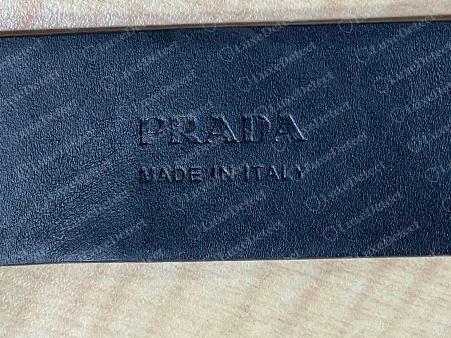Sello en caliente de un cinturón Prada auténtico: PRADA sobre MADE IN ITALY, presionado en la parte de abajo de la correa