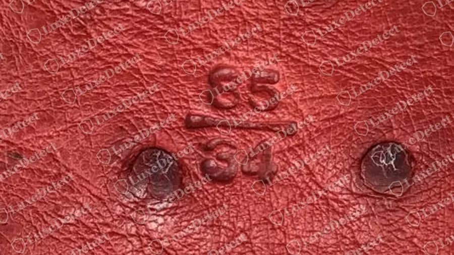 Sello de talla de un cinturón Prada auténtico: 85 sobre 34, centímetros encima de pulgadas, sobre un remate de piel roja