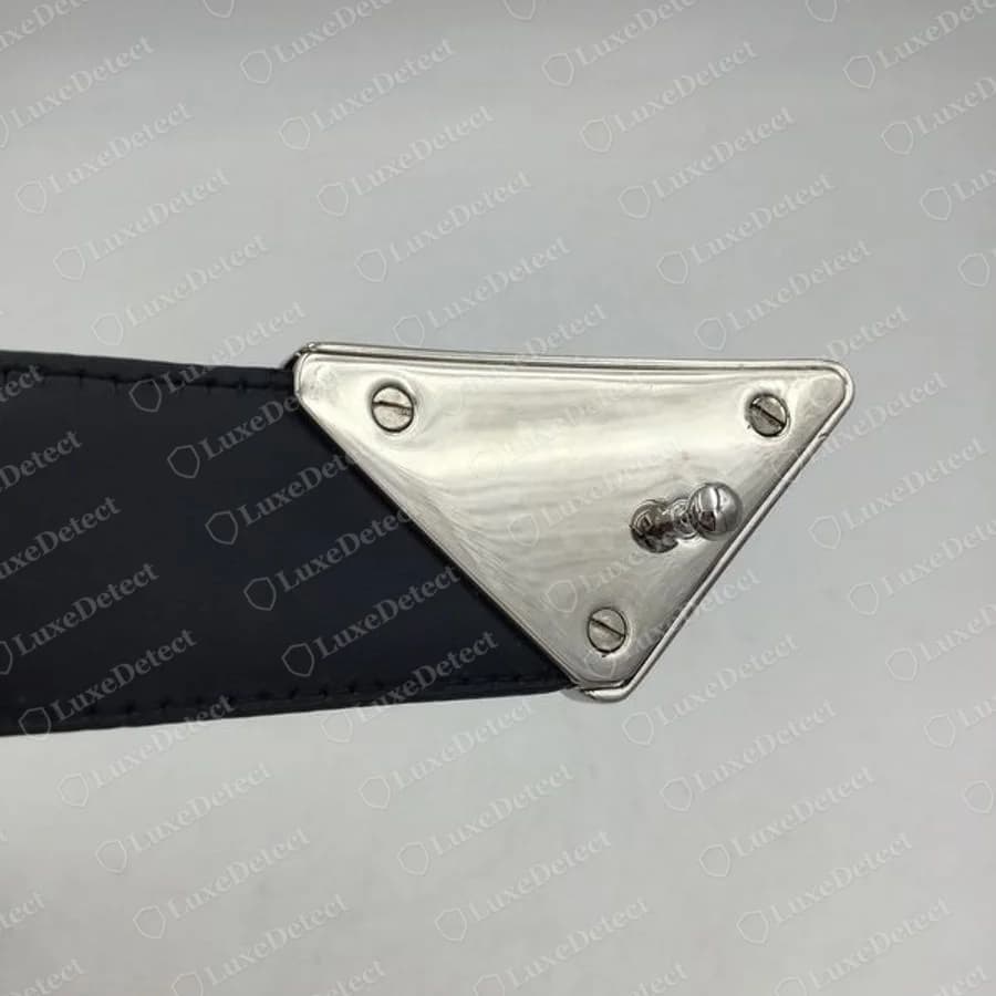 Reverso de una hebilla triangular Prada auténtica: placa pulida, tres tornillos y una aguja fija