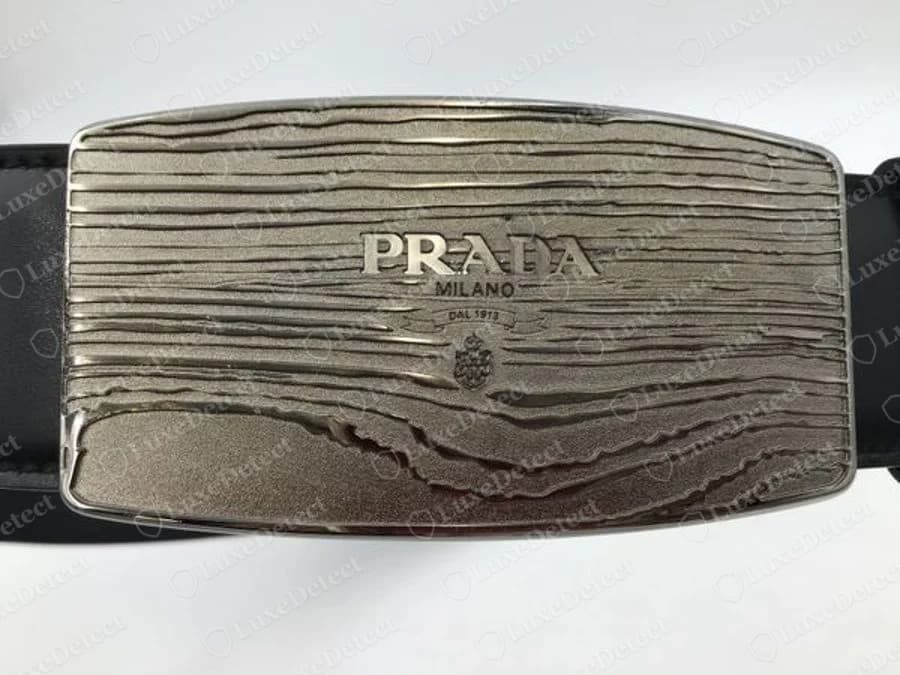 Fivela com placa Prada autêntica de textura que imita madeira: PRADA, MILANO, DAL 1913 e brasão gravados no centro