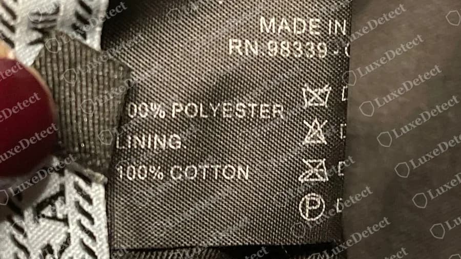 Fake Prada bucket hat with a copy of the older label: MADE IN ITALY, RN.98339, 100% POLYESTER, LINING 100% COTTON, beside a pale blue PRADA ribbon