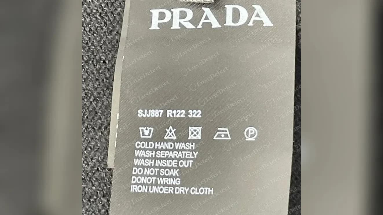 Suéter de lana Prada falsificado cuya etiqueta de cuidado copia el código del polo genuino, SJJ887 R122 322, sin línea de temporada y con la errata "IRON UNOER DRY CLOTH".