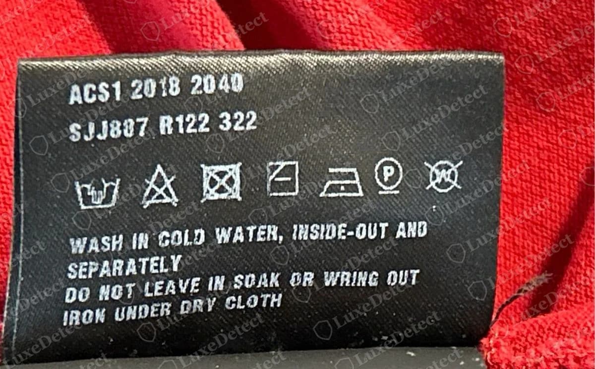 Genuine Prada piqué polo code line: ACS1 2018 2040, then SJJ887 R122 322, with care text in clean, evenly spaced letters.