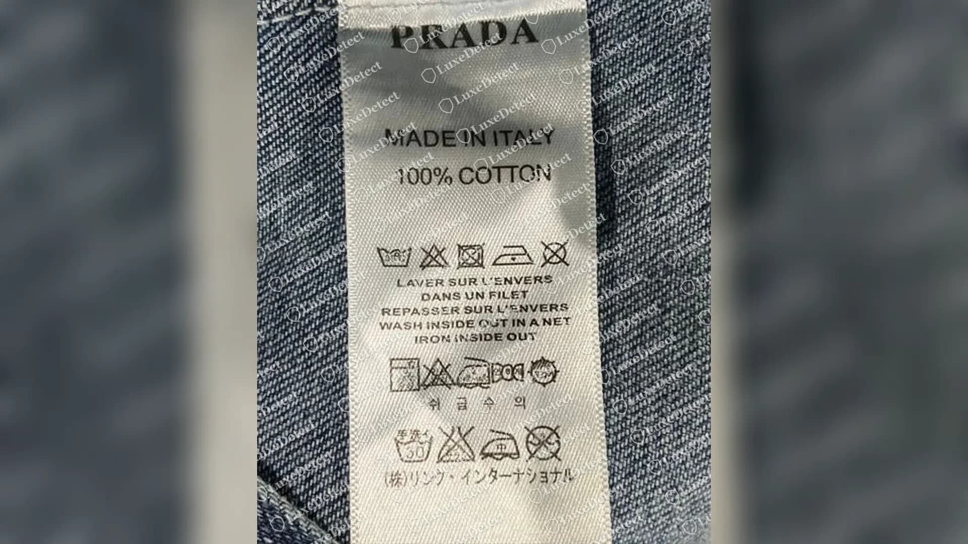 Pflegeetikett einer gefälschten Prada-Jeansjacke, das (株)リンク・インターナショナル statt Prada Japan als japanischen Importeur nennt, ohne RN-Nummer und ohne Codezeile.