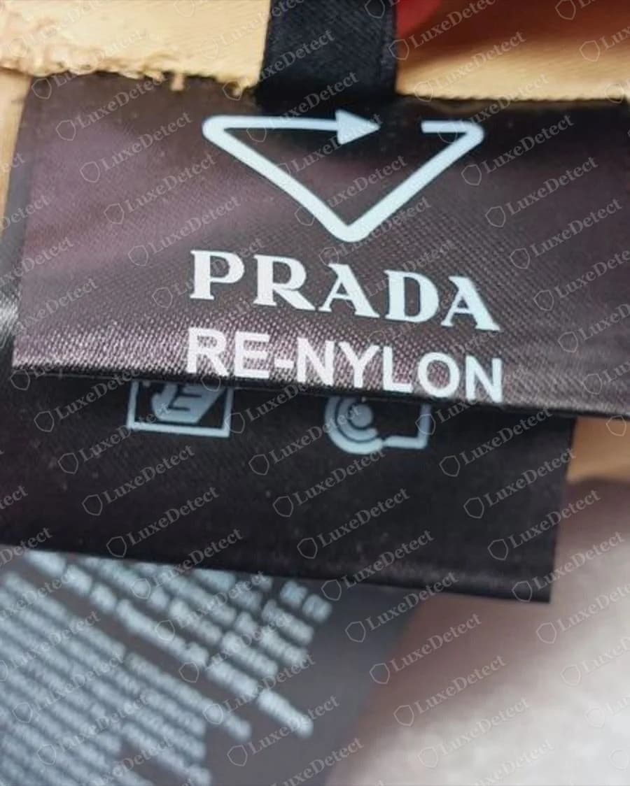 Counterfeit Prada Re-Nylon overalls label: the arrow triangle and "PRADA RE-NYLON" without the ® sign.
