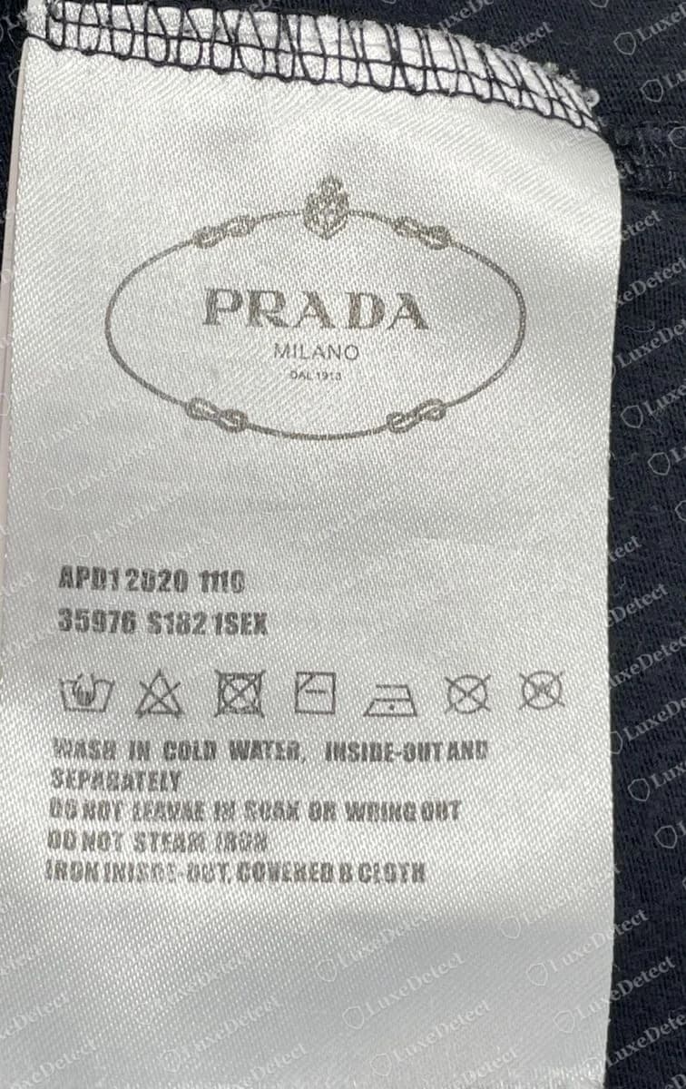 Counterfeit black triangle-print T-shirt: the care label reads APD12020 1110 / 35976 S182 1SEX under an oval Prada logo.