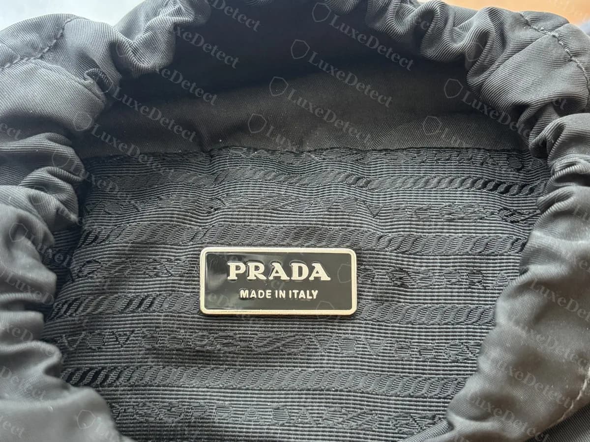 Inside the drawstring opening of a genuine Prada nylon backpack: the same rectangular plate on the jacquard lining, with the nylon gathered around it