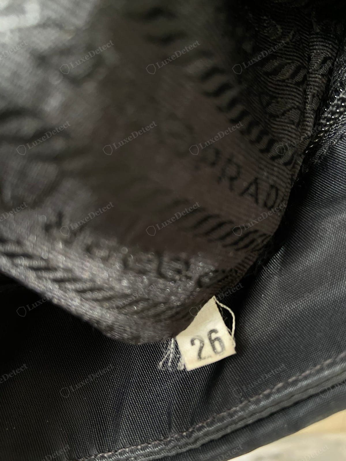 Genuine Prada Re-Edition interior, the small white numbered tag (here 26) sewn into the lining seam; the number is a production code, not a serial