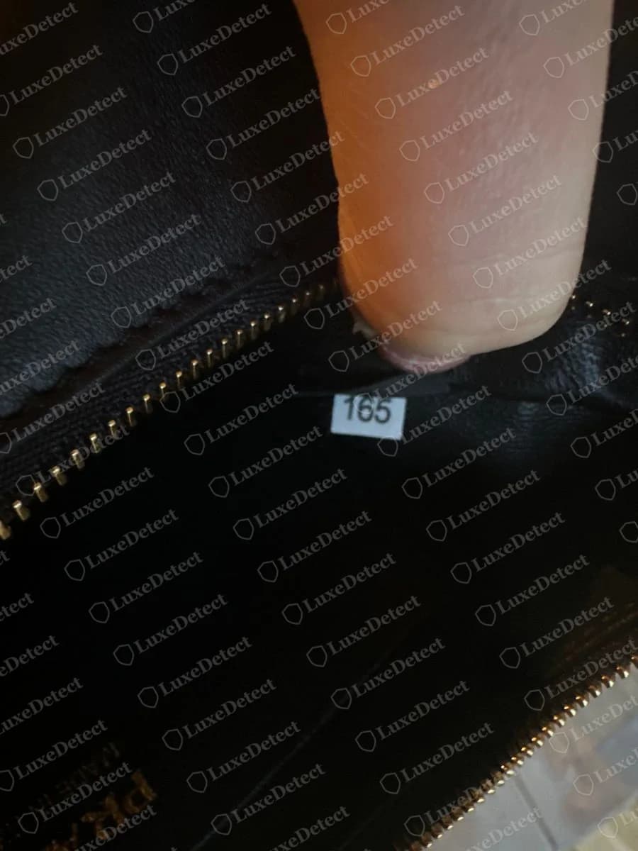 Eine echte Prada Tasche mit kleinem weißem Etikett mit der Nummer 165, in die Naht des Innenfachs eingenäht