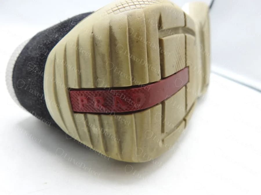 Genuine Prada Sport sneaker sole showing the molded red rubber tab reading "PRADA," recovered from a technical-line pair authenticated with a "Made in Vietnam" origin stamp