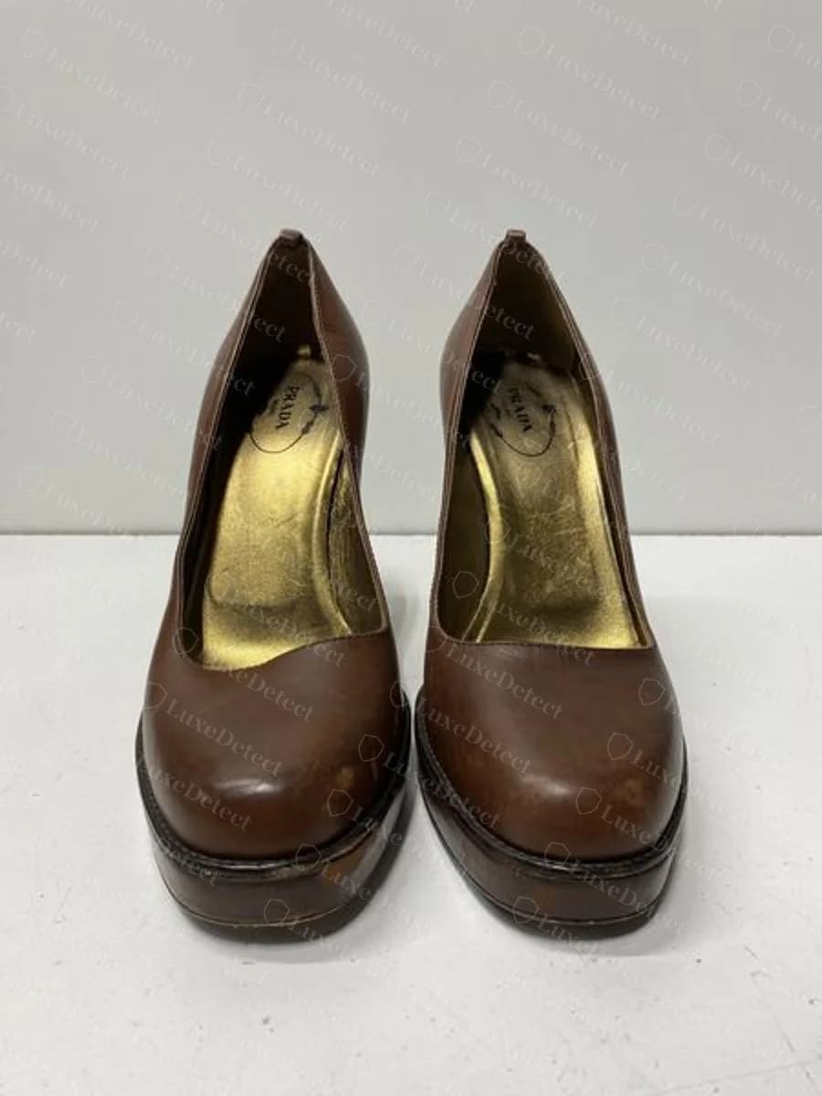 Genuine decades-old pumps, oval-outlined "PRADA" stamped in dark ink on gold-tone interior leather, a different format from the gold-foil and enamel-tab stamps shown above