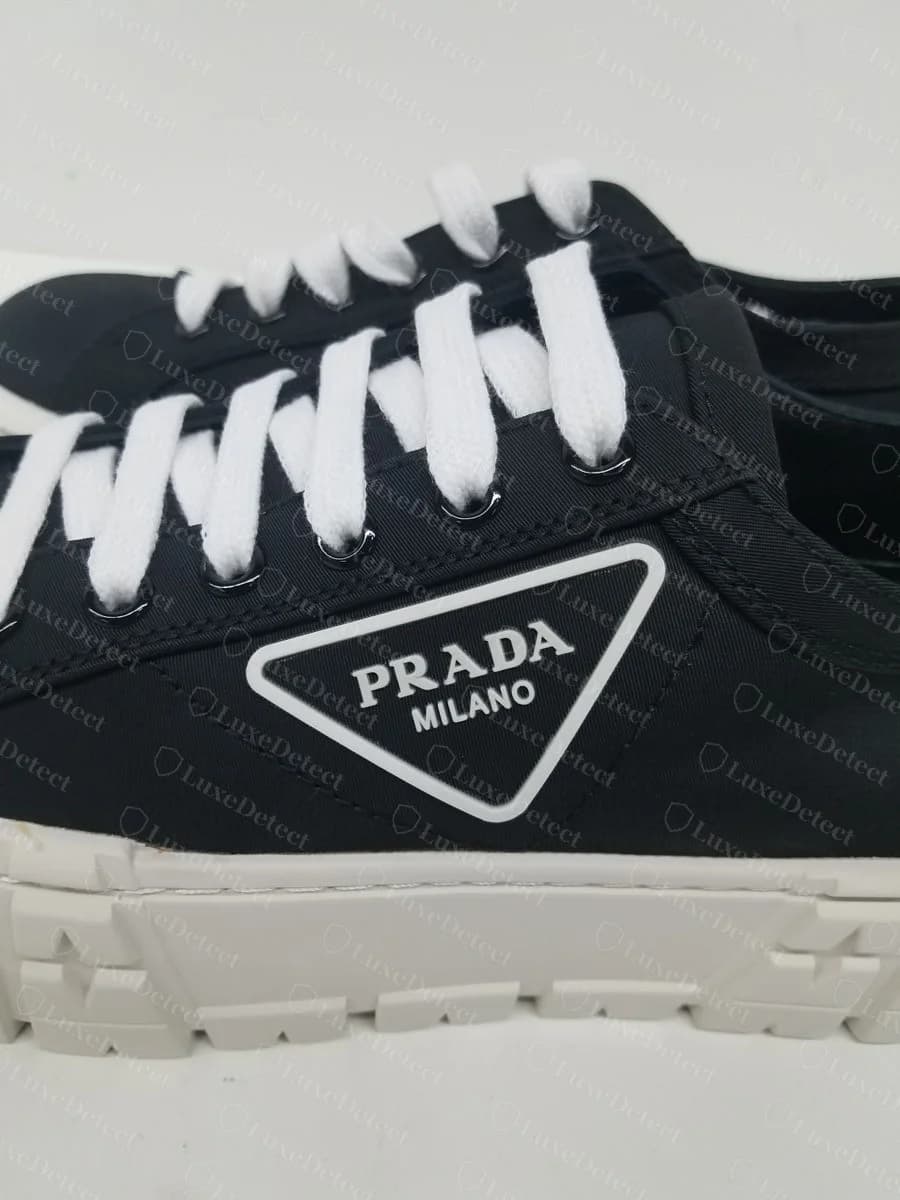 Counterfeit platform sneaker showing a printed triangle logo plaque reading "PRADA MILANO," with straight edges and clean lettering registration