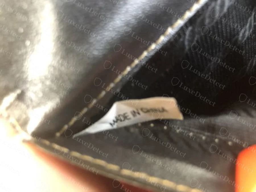 Sewn-in fabric country-of-origin label reading "MADE IN CHINA," found inside a counterfeit wallet styled as an Italian-made exotic-leather piece