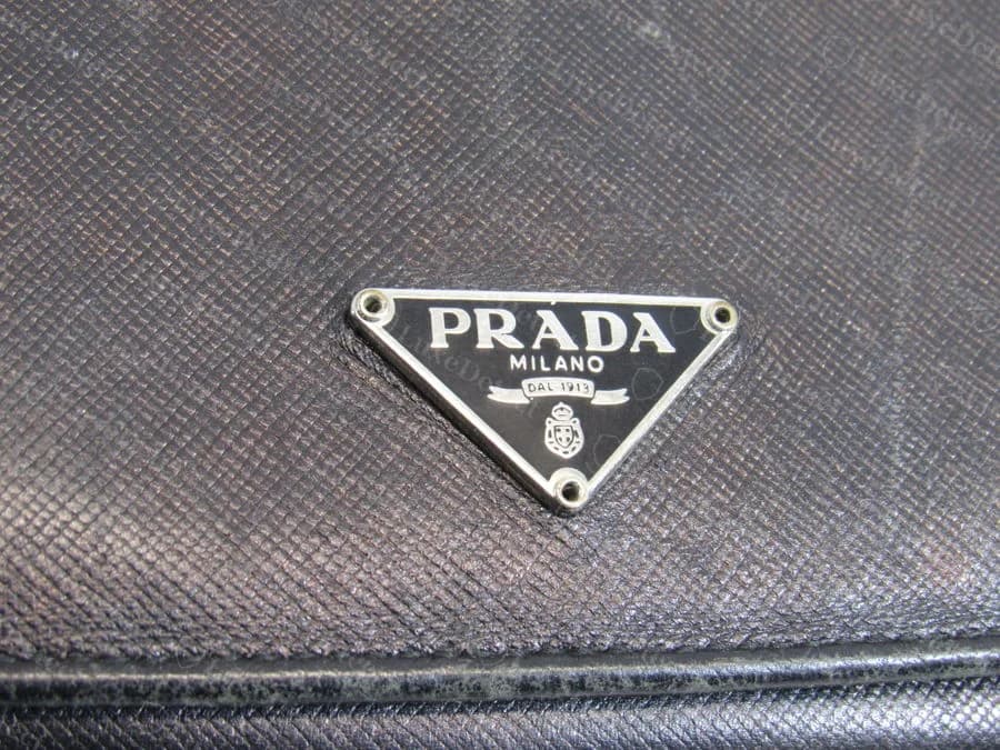 Prada triangle logo plaque, authentic — clean beveled edges, sharp foil-lettered text