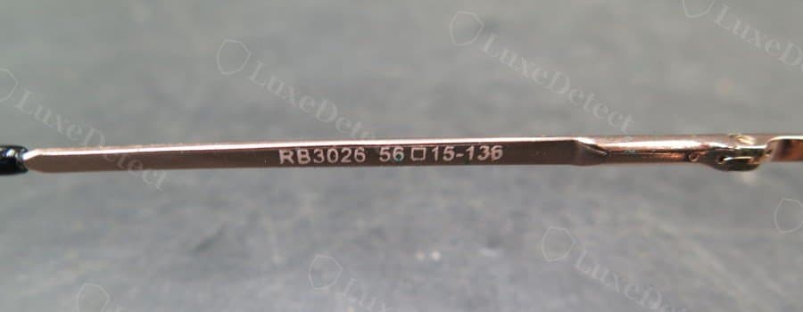 Counterfeit temple engraving: the model code is legible but the strokes are thinner and less consistent in depth than the genuine mark above