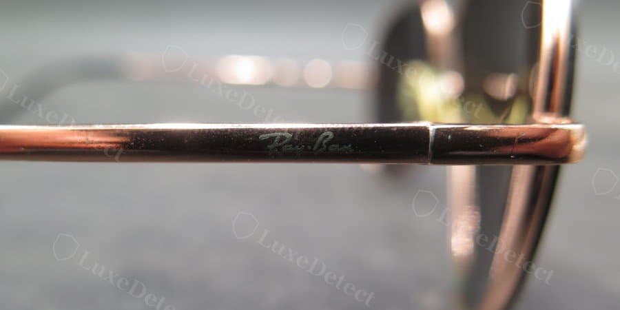 Counterfeit Ray-Ban script on the temple: flatter, greyish laser mark with thinner strokes and less contrast against the metal