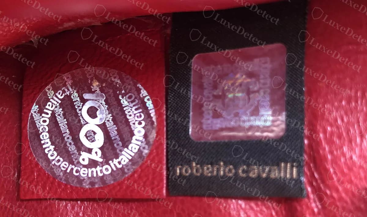 Genuine Roberto Cavalli red leather bag lining with a round clear 100 percent Italian seal beside a black woven tag with a hologram and roberto cavalli in gold lettering