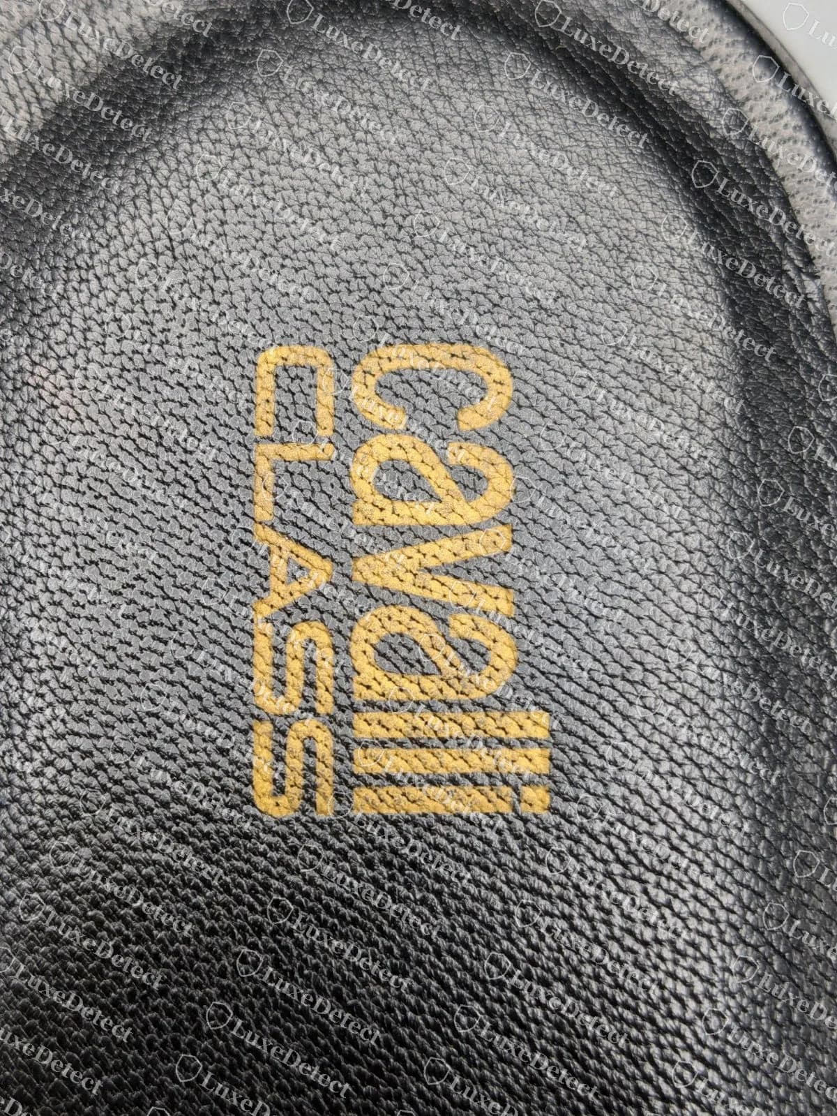 Estampado de foil dorado en la plantilla de Cavalli Class original, sobre piel negra, dentro de un mocasín mule con estribo, que dice cavalli apilado sobre CLASS en una tipografía cuadrada