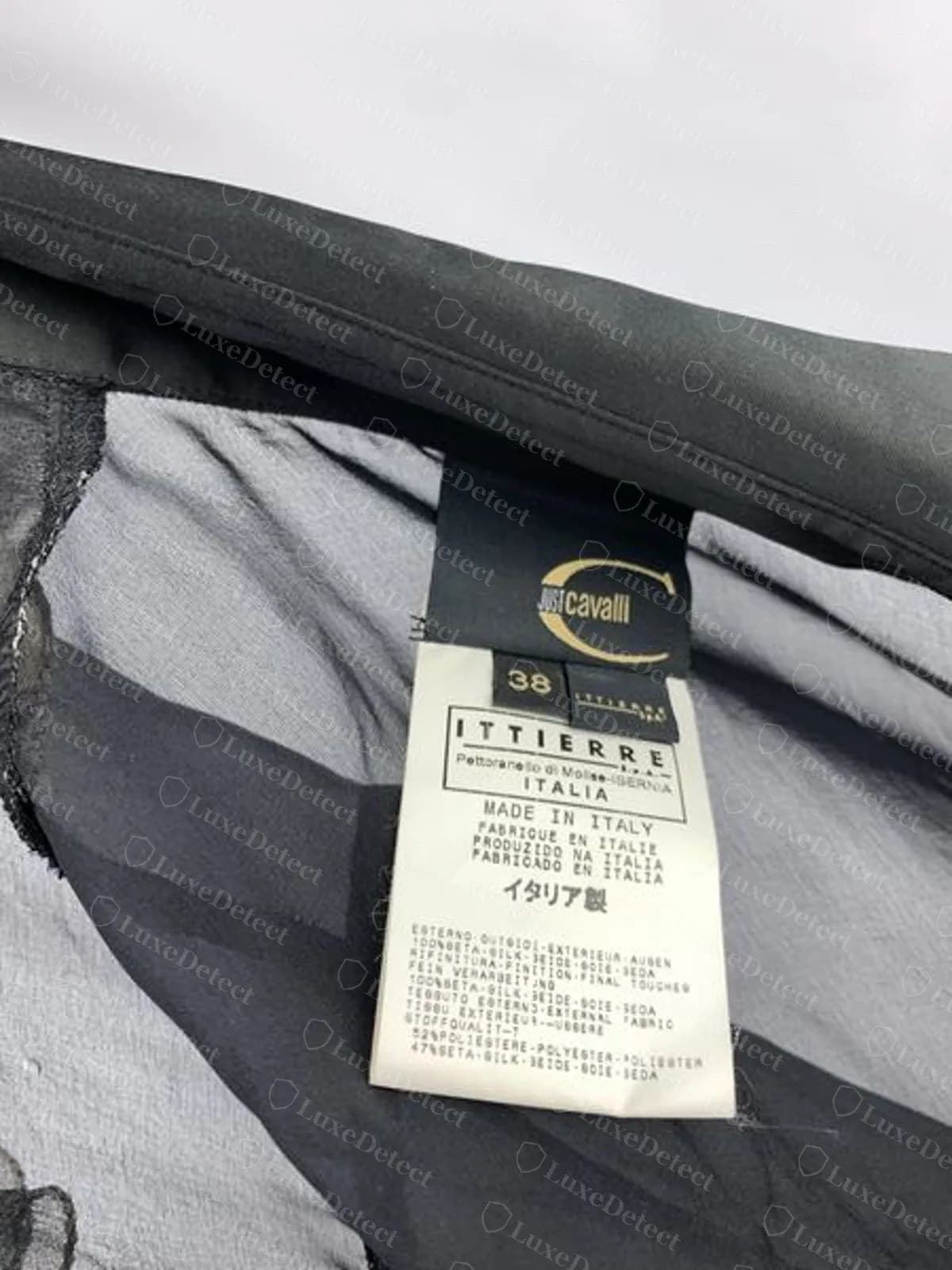 Genuine Just Cavalli black neck label with a gold C and JUST cavalli, size 38, above a white Distributed by Ittierre tag reading Made in Italy in several languages, inside a sheer black blouse