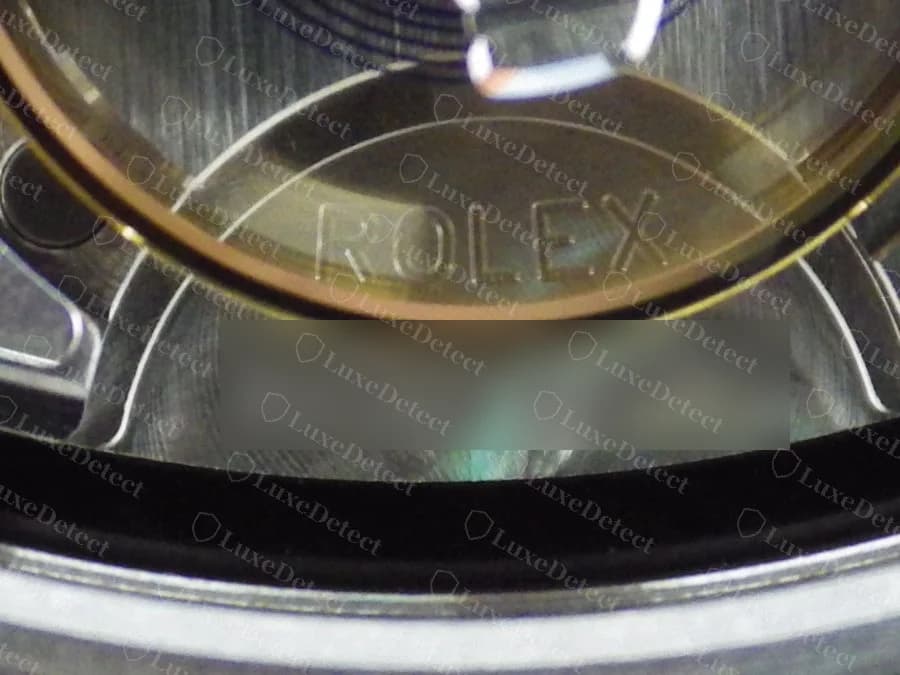 Um Datejust moderno original visto pelo cristal na posição das 6 horas: ROLEX gravado na borda interna do mostrador com o número de série gravado abaixo (número de série desfocado), os caracteres nítidos e com espaçamento uniforme