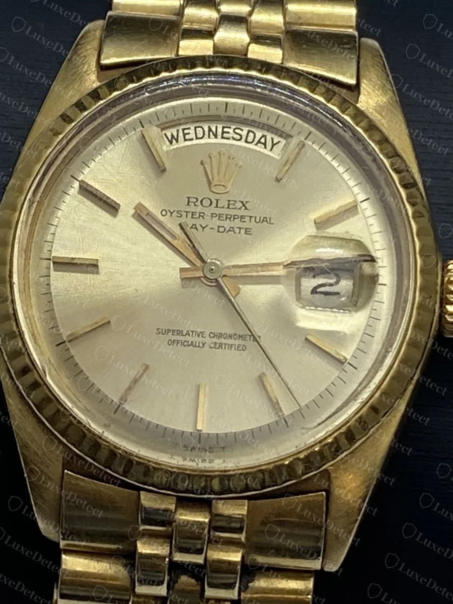 Um mostrador original de ouro de um Rolex Day-Date em pulseira estilo Jubilee: o dia da semana escrito por extenso em uma janela na posição das 12 horas, a data em uma janela na posição das 3, o texto ROLEX Oyster-Perpetual Day-Date, uma luneta canelada de ouro
