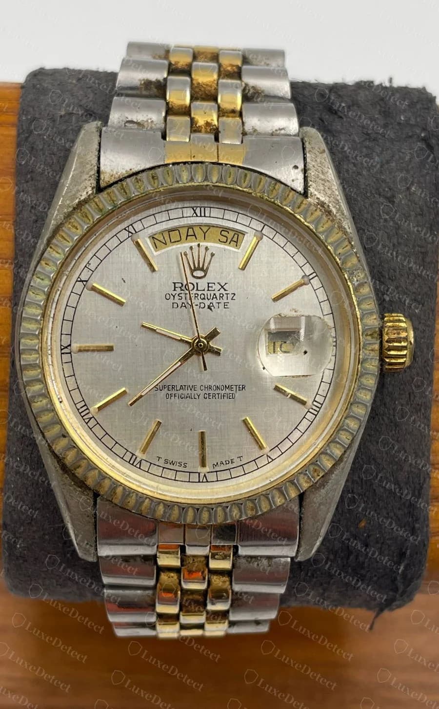 Falso "Oysterquartz Day-Date" bicolor: aço e ouro em pulseira estilo Jubilee com luneta canelada, e uma janela de dia cujo texto está truncado e diz "NDAY SA"