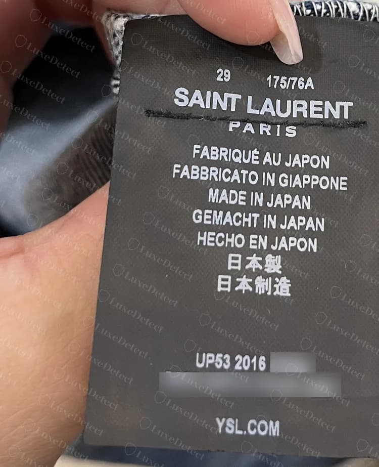 Genuine Saint Laurent Paris care label from a denim garment, made in Japan, with the made-in line in five European languages plus Japanese and Chinese; the running number and style line are blurred.