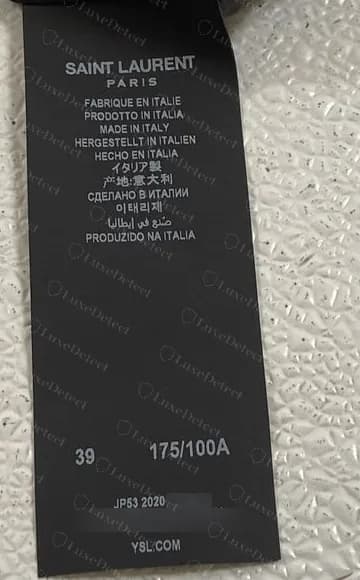 Etiqueta de cuidados Saint Laurent Paris de 2020 original, feita na Itália, com bloco de fabricação mais longo, com linhas em russo, coreano, árabe e português acrescentadas; o ano está visível, o resto do código está desfocado.