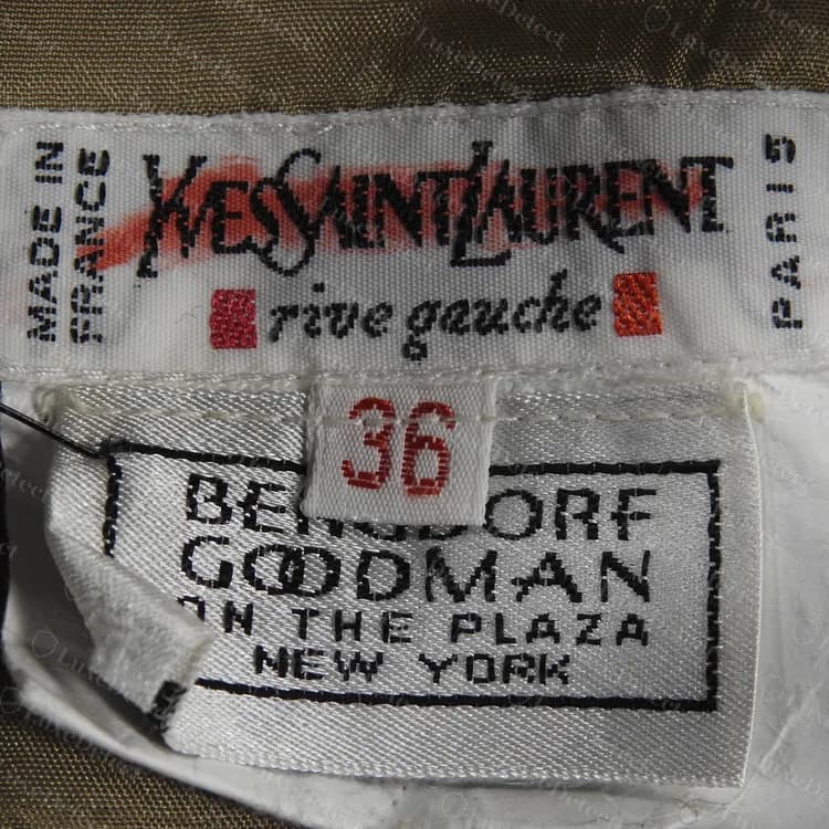 Ancienne étiquette rive gauche authentique avec des carrés rouges, MADE IN FRANCE et PARIS imprimés sur les côtés et un numéro de taille rouge, au-dessus d'une étiquette de revendeur de grand magasin.
