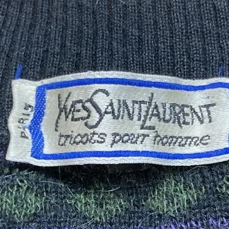 Genuine blue-bordered woven "tricots pour homme" label with PARIS up the left side, at the neck of a patterned sweater.