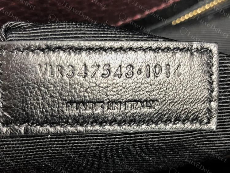 Pestaña con el código de un Sac de Jour genuino en otro bolso: una pestaña de cuero liso junto al bolsillo con cremallera, con prefijo de letras, número de estilo de seis dígitos, punto elevado y bloque de cuatro dígitos, y MADE IN ITALY debajo