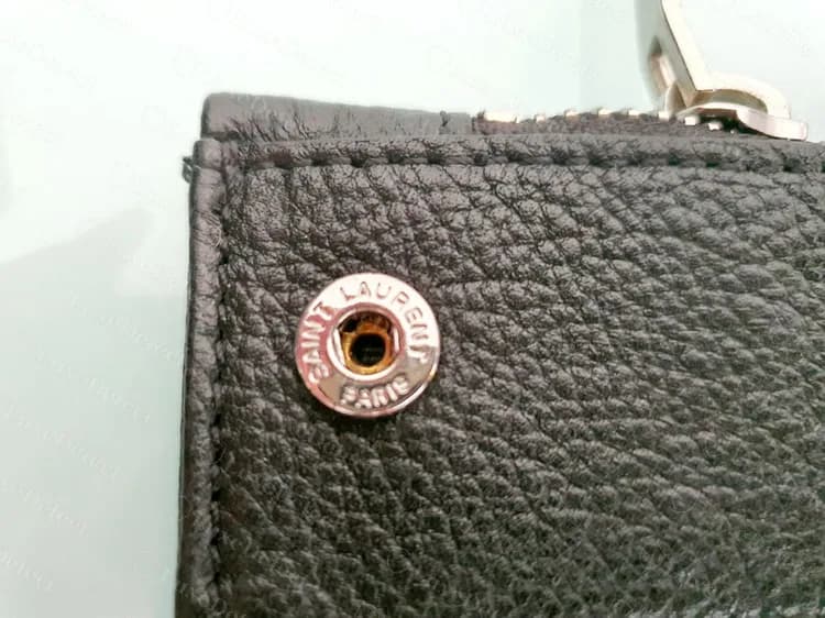 Genuine Sac de Jour side snap: SAINT LAURENT stamped around the rim and PARIS below, on grained black leather
