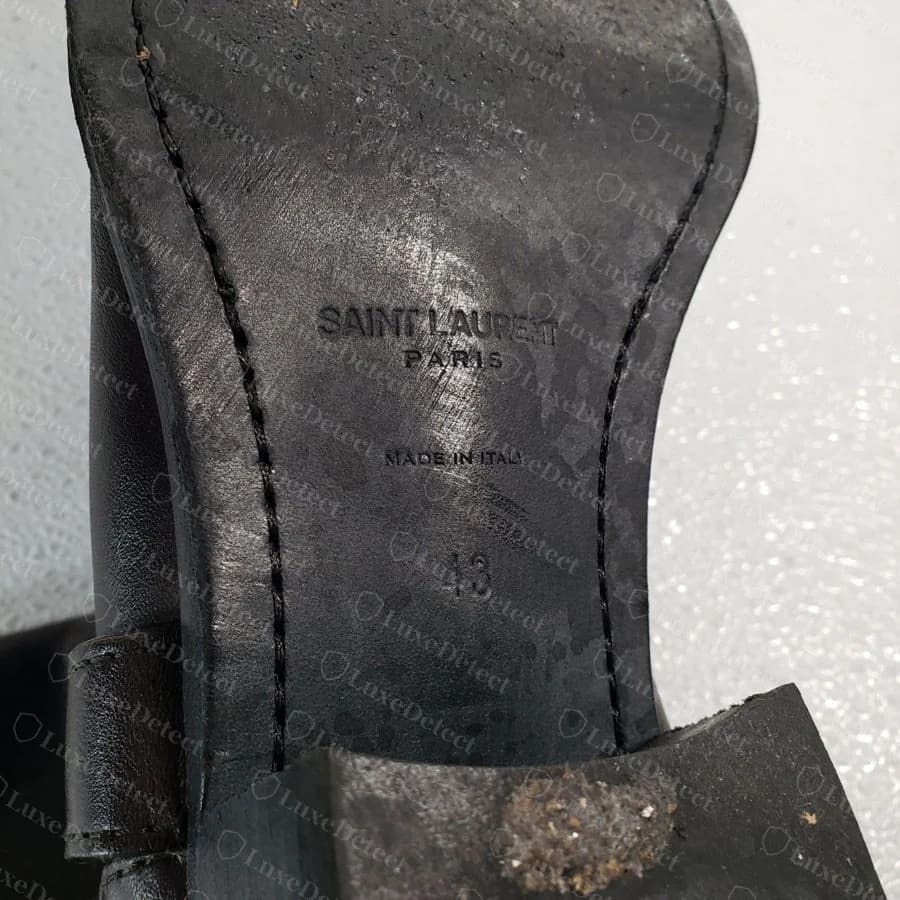 Genuine "SAINT LAURENT PARIS" block-capital stamp heat-pressed into the outsole leather of a men's harness boot, with "MADE IN ITALY" and the size below.