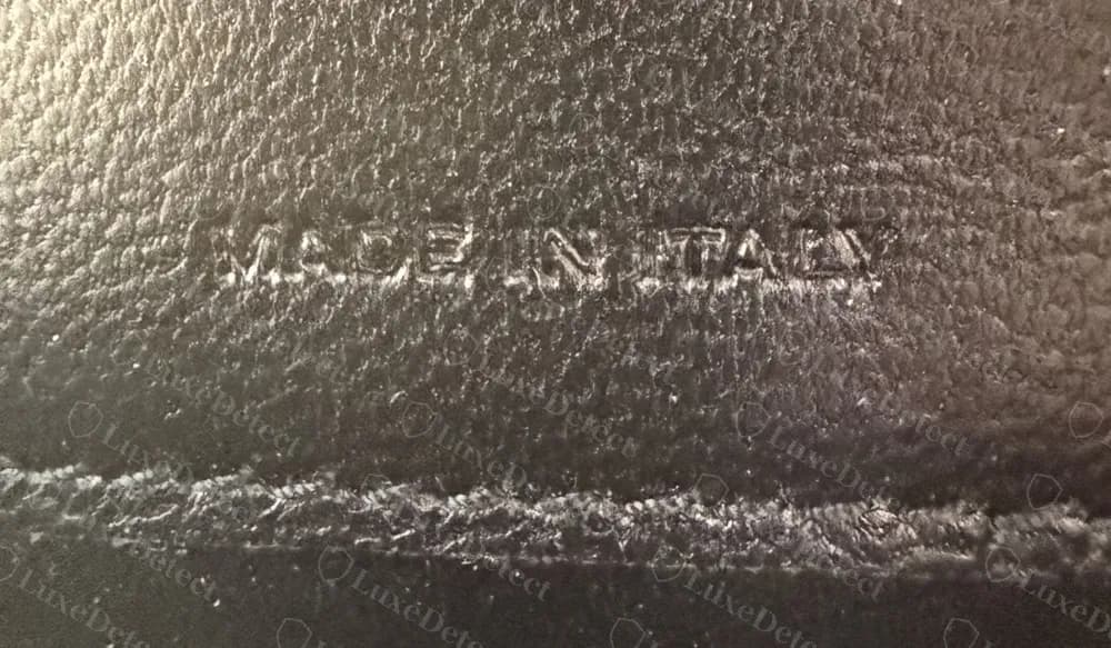 Echt: Nahaufnahme der ins Leder gepressten Zeile MADE IN ITALY, kontrastarm und flach