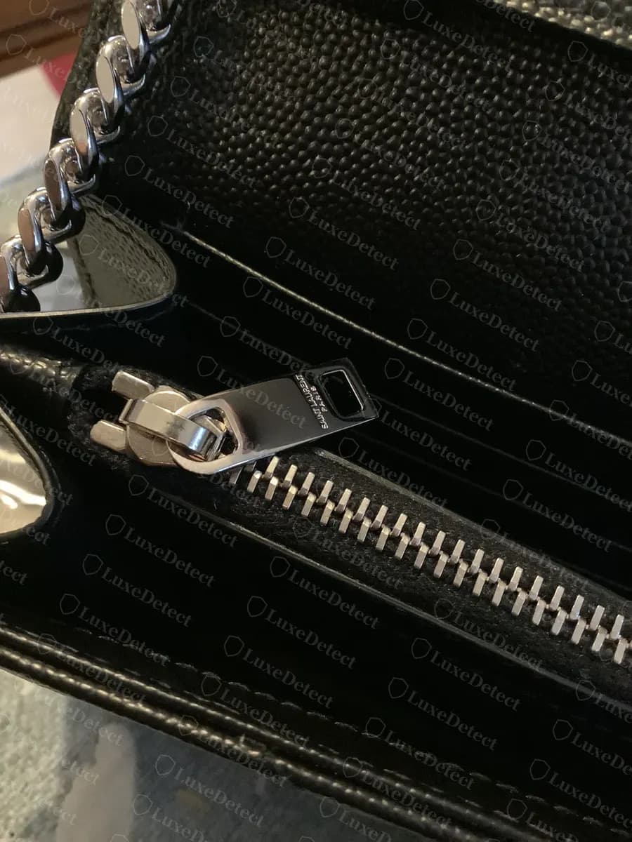 Genuine chain strap visible at the top edge of the interior zip pocket, matching the hardware finish of the zip pull
