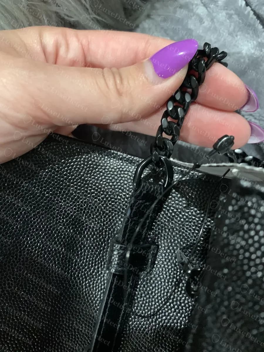 Genuine curb-link chain held against the quilted exterior leather, showing uniform link size and finish