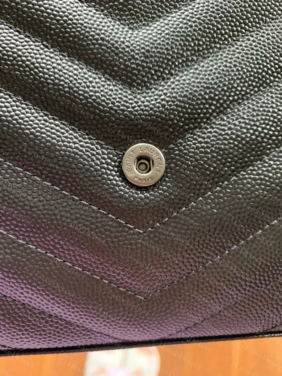 Genuine front snap closure, stamped SAINT LAURENT PARIS in two centered lines, set flush into the quilted leather